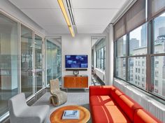 a living room filled with furniture and large windows next to a flat screen tv mounted on a wall