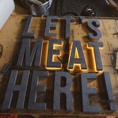 the words let's meat here are lit up in neon letters on a table