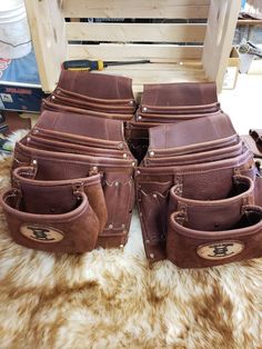 several brown leather purses sitting on top of a fur covered floor