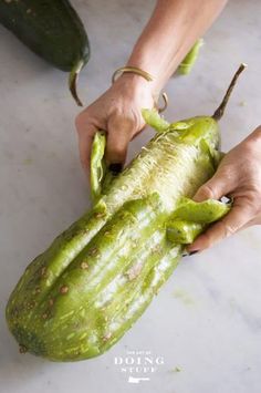 someone is peeling an open cucumber on the counter with their hands and fingers