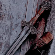 two medieval swords with intricate carving on them sitting next to each other in front of a wooden door