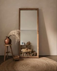 a mirror sitting on top of a wooden floor next to a table and stools