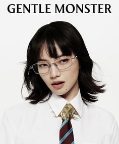 a woman wearing glasses and a tie is standing in front of a poster for the movie gentle monster