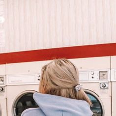 a woman sitting in front of a stack of washers with her back to the camera