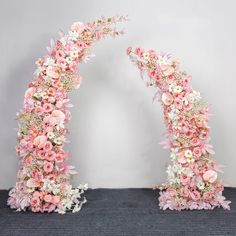 an arch made out of pink and white flowers on top of a carpeted floor