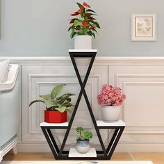 three potted plants are sitting on top of a triangular shelf in the corner of a room