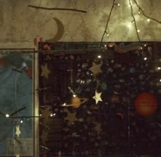 an image of a window with stars and planets in the glass, as well as lights on the wall