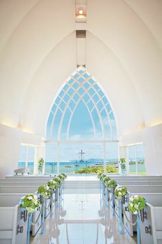 the interior of a church with white walls and stained glass windows, decorated with flowers