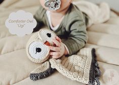 a baby with a pacifier in his mouth laying on a bed next to a stuffed animal