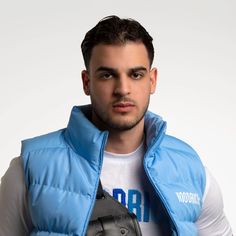 a young man wearing a blue vest and holding a baseball glove in his right hand