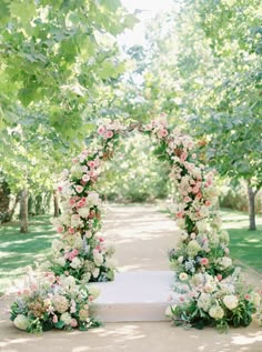 an outdoor ceremony setup with flowers and greenery on the ground, surrounded by trees