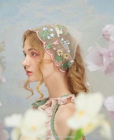 a woman wearing a veil with flowers in the background