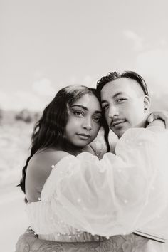 a man and woman embracing each other on the beach