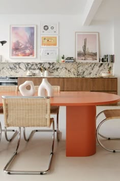 a dining room table with chairs and pictures on the wall