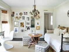 a living room filled with white furniture and pictures on the wall above it's headboard