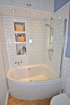 a white bath tub sitting inside of a bathroom next to a toilet and shower head