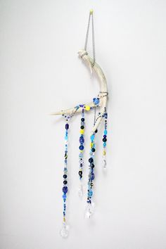 a wind chime hanging from the side of a white wall with beads on it