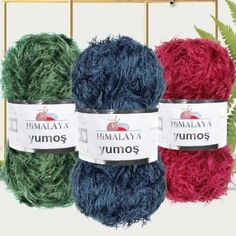 three balls of yarn sitting next to each other in front of a rack with plants