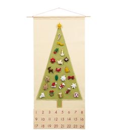 a christmas tree with pins on it hanging from a wall mounted calendar board in front of a white background