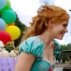 a man and woman standing next to each other in front of a fountain with balloons