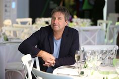 a man sitting at a table with wine glasses on it and looking off to the side