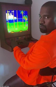 a man sitting in front of a tv playing a game on the nintendo 64 console