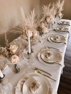 the table is set with white plates and silverware