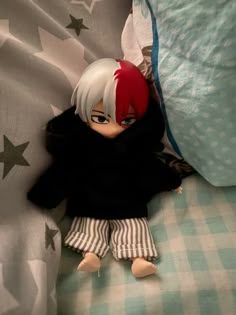 a doll is laying on a bed with stars around her head and black shirt, striped pants, and red hair