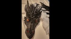 a dragon head hanging from the side of a door with red eyes and black wings