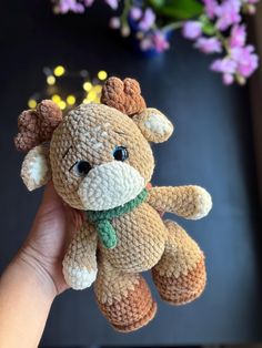 a hand holding a small brown and white stuffed animal