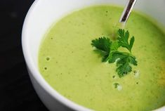 a white bowl filled with broccoli soup and garnished with parsley