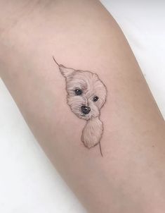 a small white dog on the left arm with a tiny nose and tail tattoo design