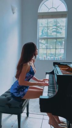 a woman sitting at a piano in front of a window