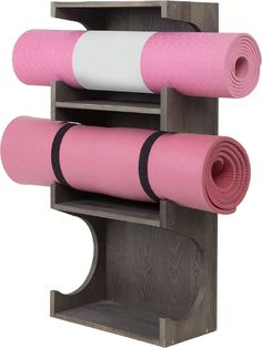 two pink yoga mats are placed on top of each other in front of a wooden shelf