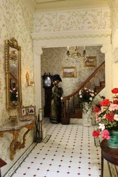 the hallway is decorated with floral wallpaper and antique furniture, along with vases of flowers