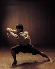 a man standing on one leg with his arms stretched out in the air while wearing boxing gloves