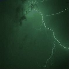 a green and black photo with lightning in the sky