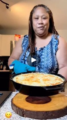 a woman in blue gloves is holding a pan with food on it and smiling at the camera