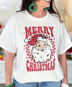 a woman wearing a merry christmas t - shirt with santa clause on the front and green earrings