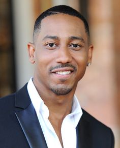 a close up of a person wearing a suit and tie with a smile on his face