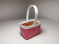 a pink and white bag sitting on top of a table next to a brown piece of bread