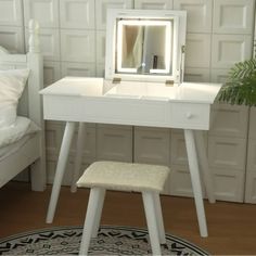 a white vanity table with a mirror and stool in front of it on a rug