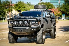 a black truck is parked in a parking lot with its lights on and four wheel drive