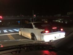 a white car is parked on the side of the road in front of a red traffic light