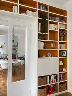 an open bookcase with many books on it in a living room next to a dining room table