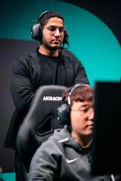 a man sitting in front of a computer monitor wearing headphones on top of his head