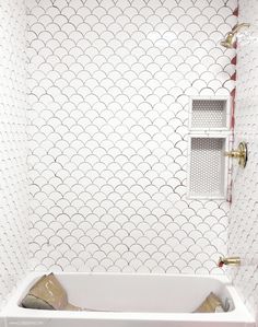 a white bath tub sitting inside of a bathroom next to a wall mounted shower head