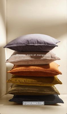 a stack of pillows sitting on top of each other in front of a white wall