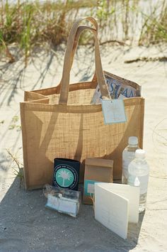 a bag sitting on top of a sandy beach next to water bottles and other items