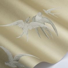 two white birds flying in the sky on a gold and silver wallpaper design with metallic foil